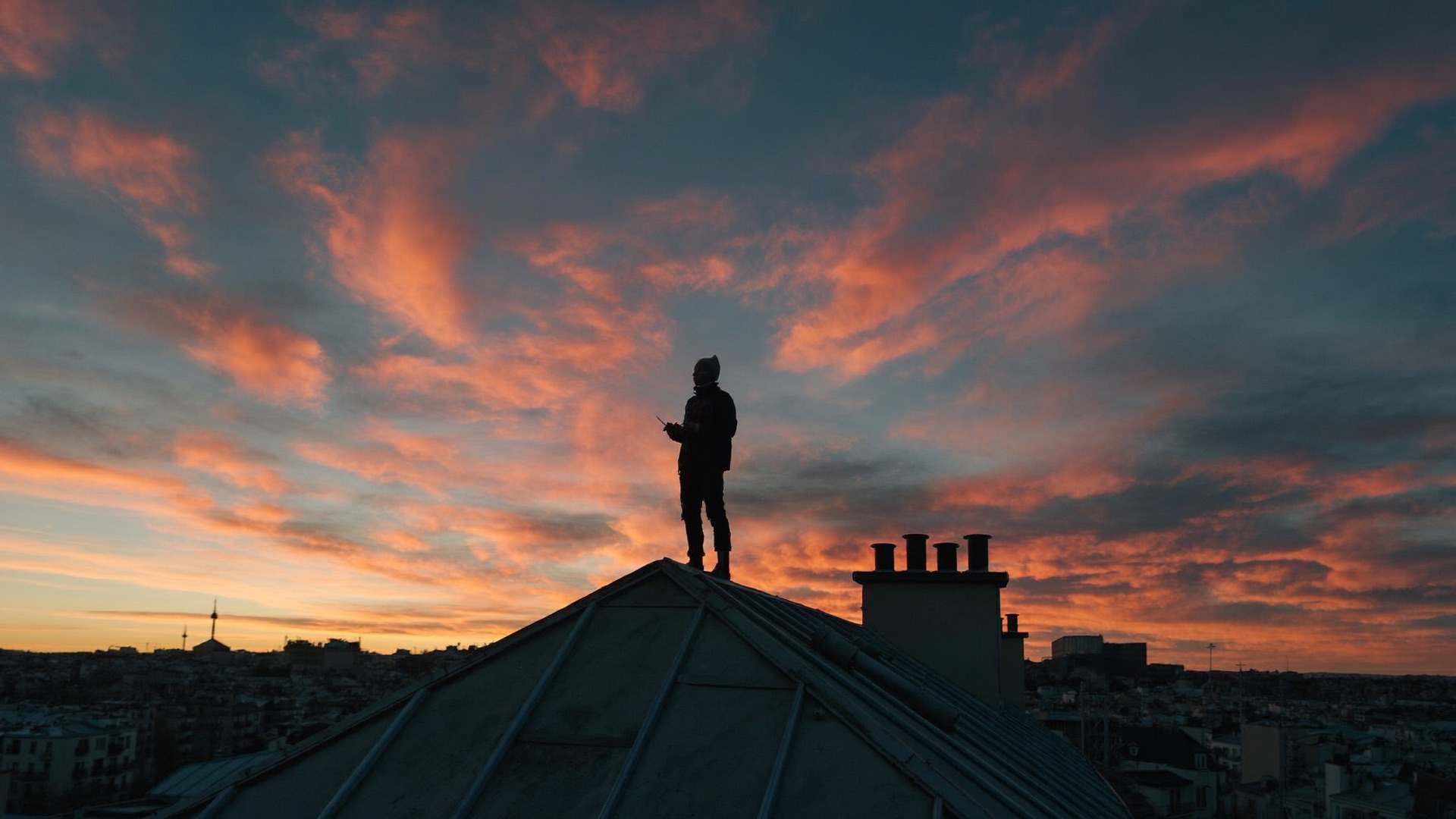 Dachdecker steht bei Sonnenaufgang auf dem First eines Daches über der Stadt