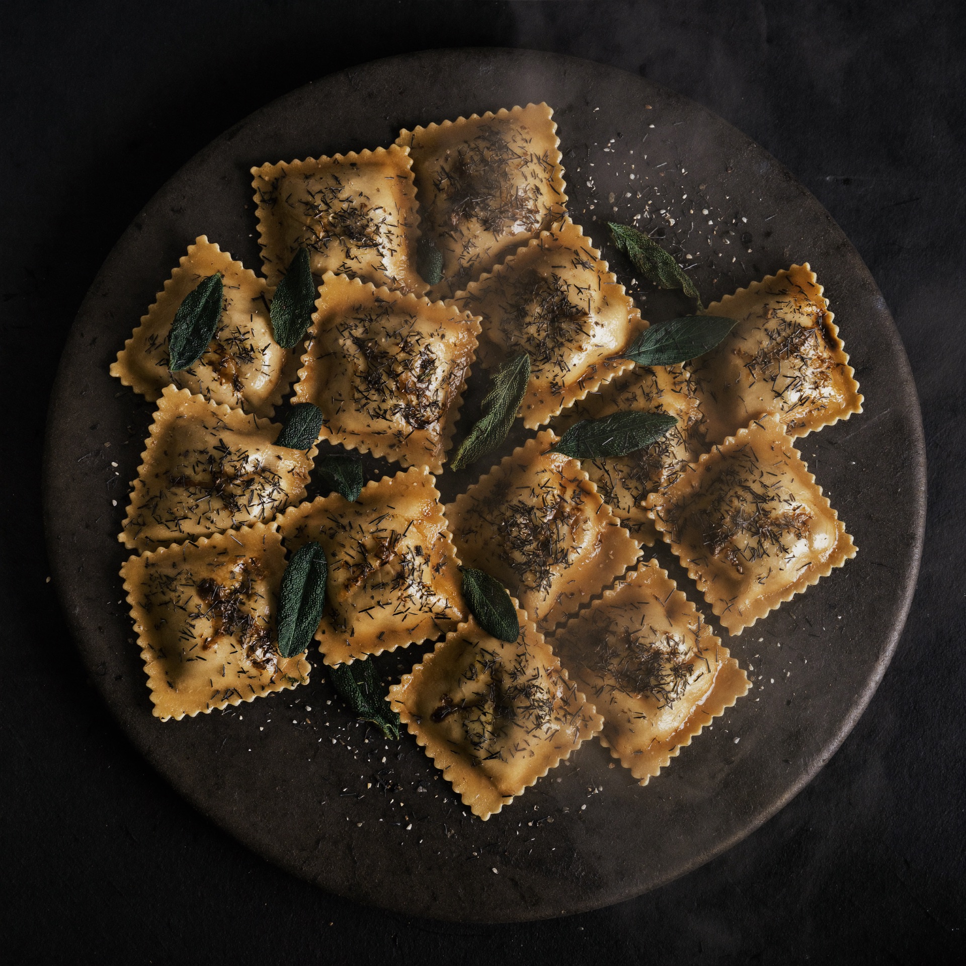 Ravioli mit Salbei und brauner Butter auf dunklem Steinteller