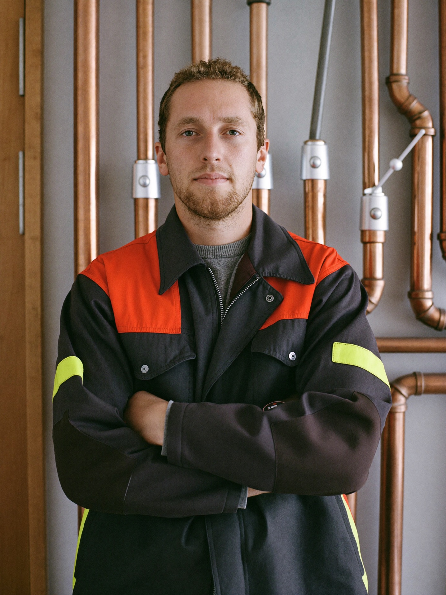 Anlagenmechaniker des Rohrwerk-Teams vor einer Wand mit Kupferleitungen